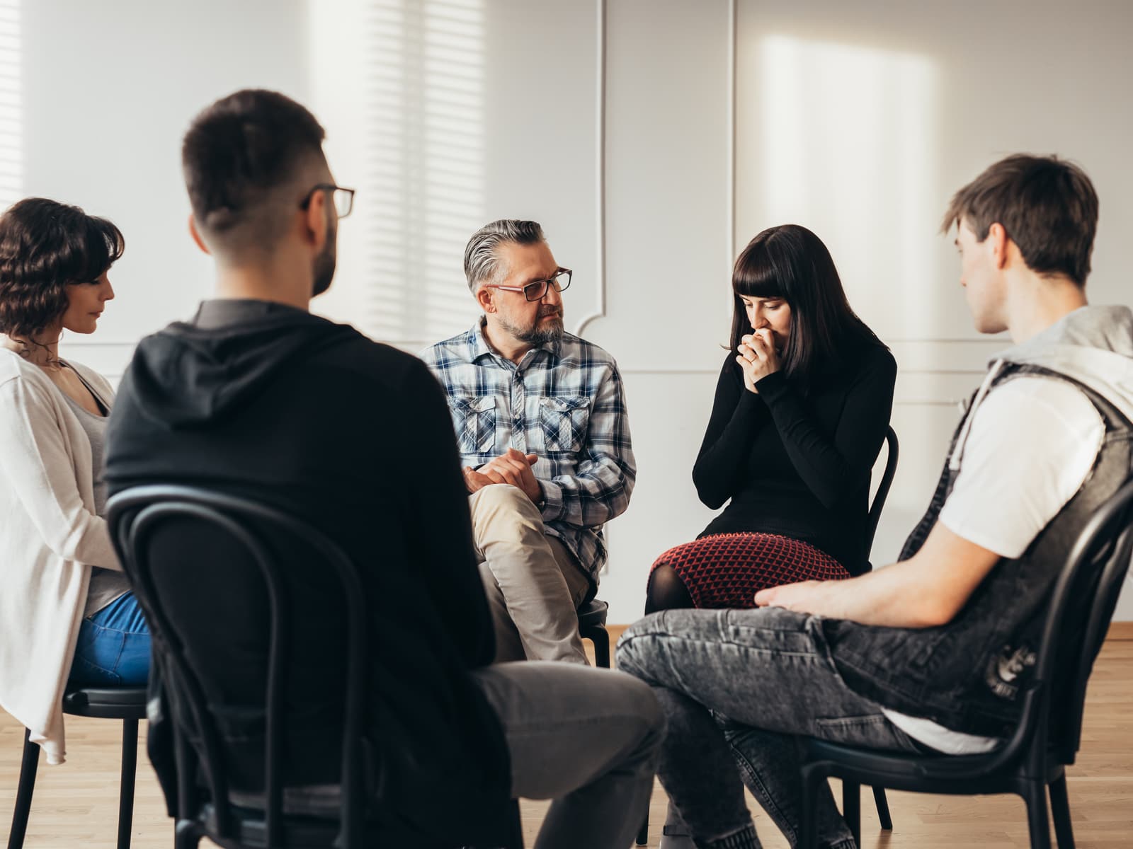 Five people sitting in a circle, mid-conversation.